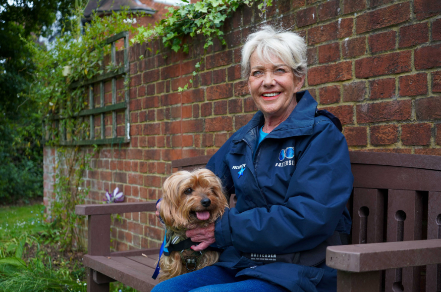 Longest serving volunteer Ann Palmer Battersea volunteer sitting on bench with dog