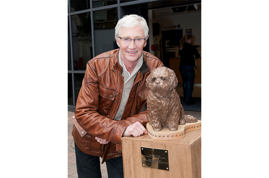 Paul O Grady next to a dog statue onsite
