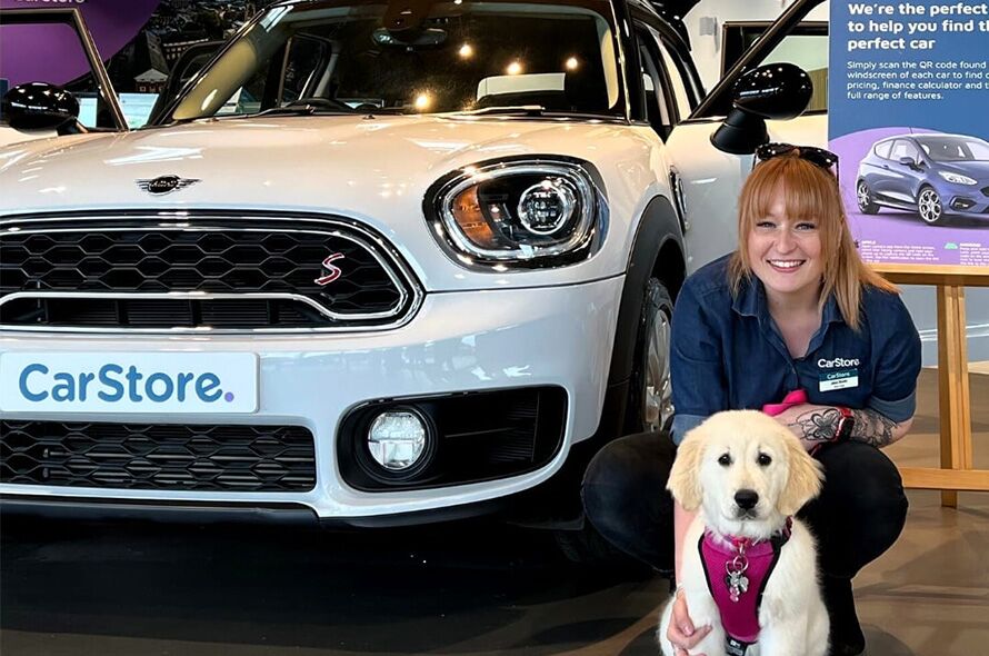 CarStore employee with a dog in front of a car