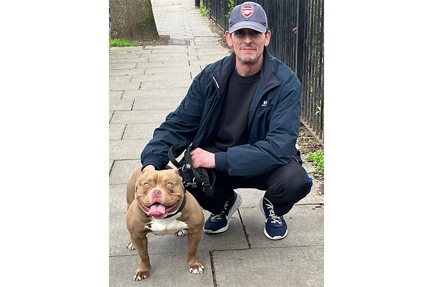Man squatting next to a dog.