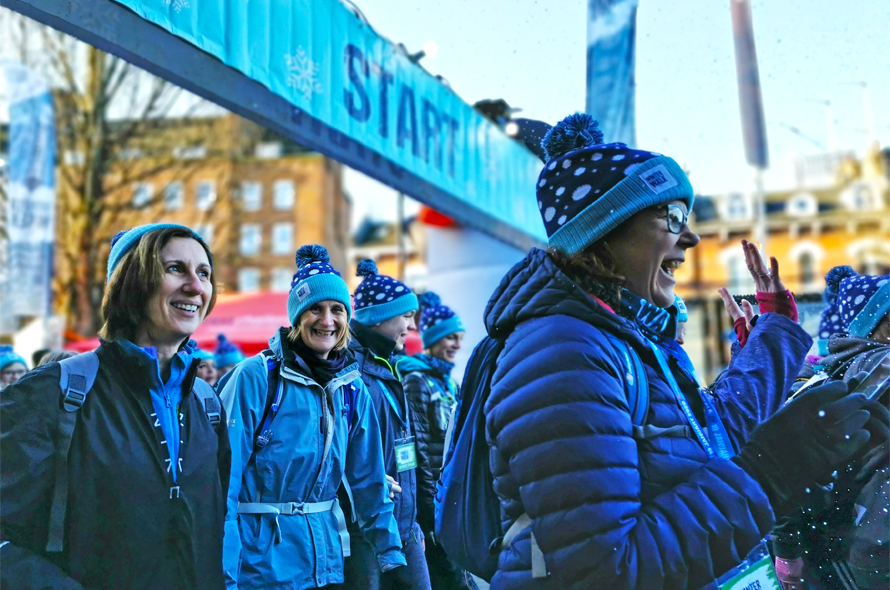 Several people wearing matching blue hats and jackets, gathered closely in a friendly atmosphere.