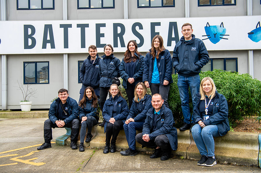 Battersea Canine Behaviour team wearing branded navy raincoats in front of a Battersea building