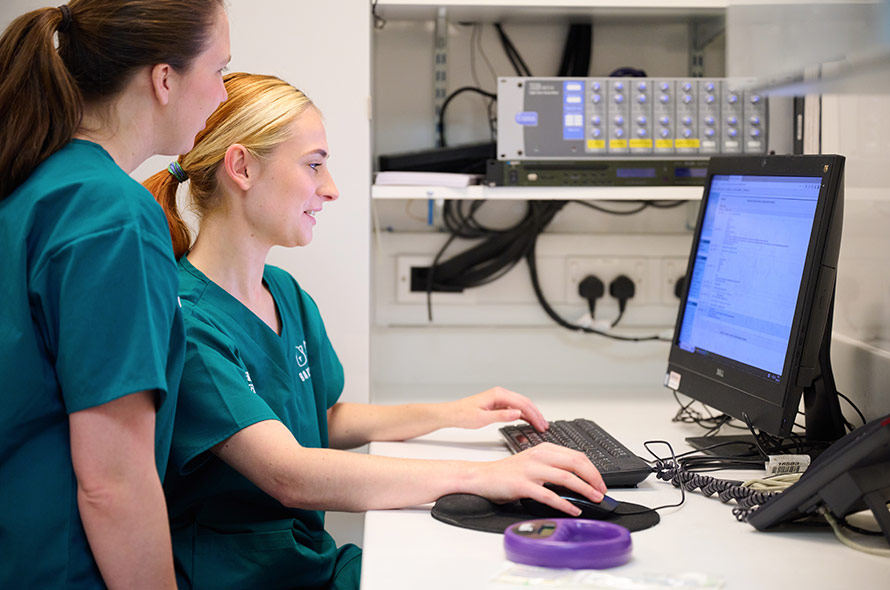 Two members of the veterinary clinic team in the office looking at a desktop screen