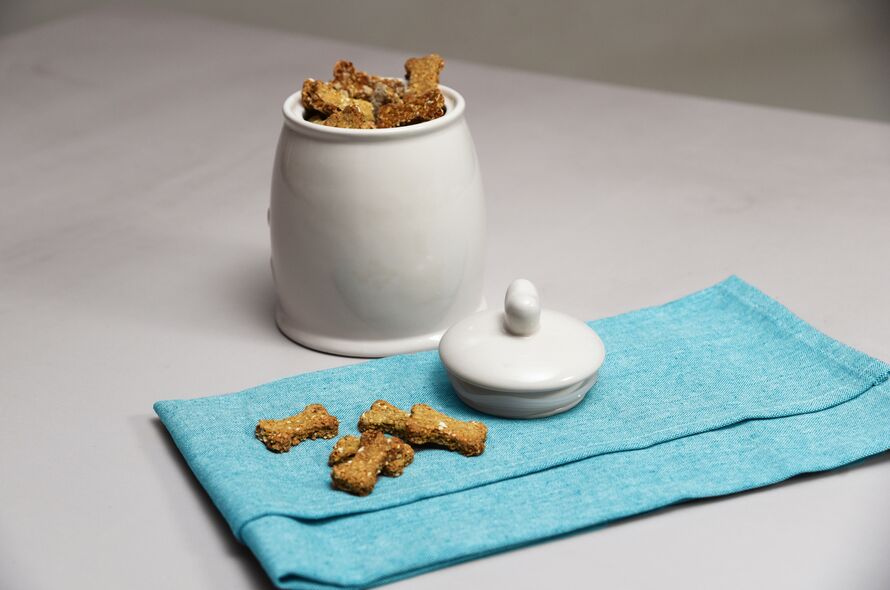 A white ceramic jar filled with homemade dog biscuits