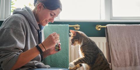 Woman and her cat looking at a bottle 