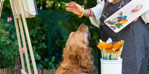 A person painting and a dog looking up at them