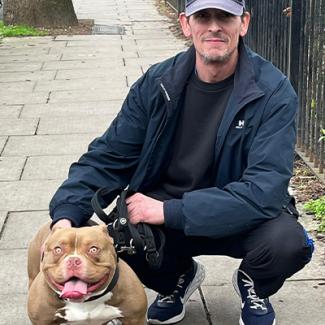 Man squatting next to a dog. 
