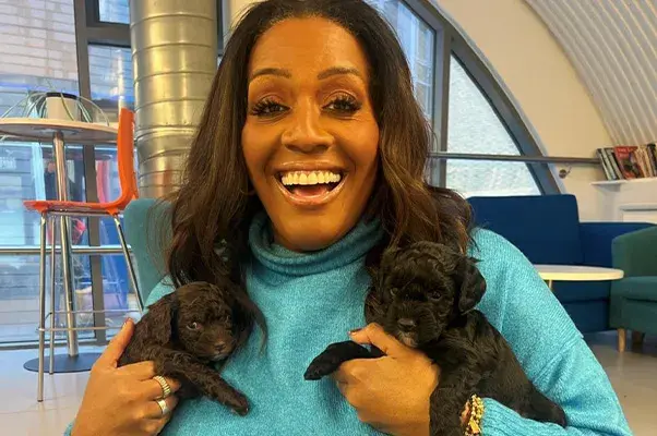Alison Hammond holding two black puppies