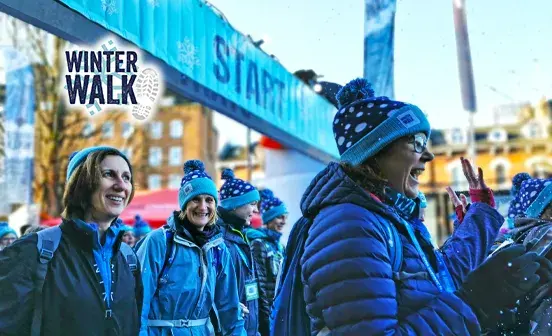 Several people wearing matching blue hats and jackets, gathered closely in a friendly atmosphere.