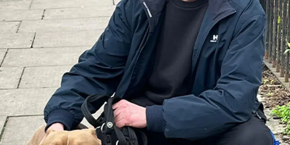 Man squatting next to a dog. 