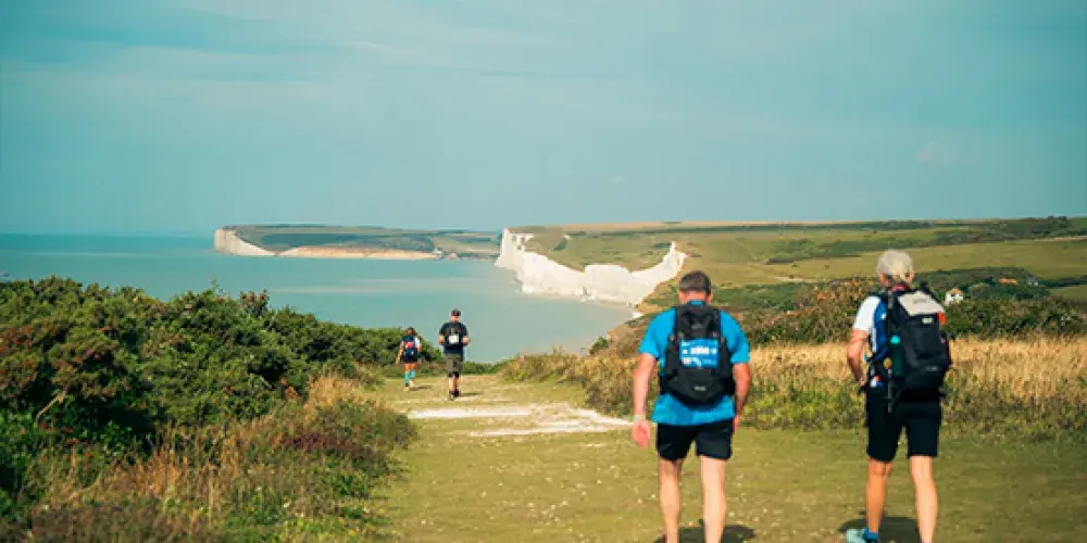 Three people trekking along a coastal path