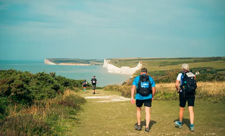 Three people trekking along a coastal path
